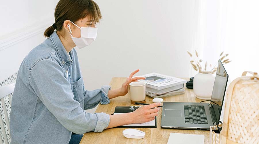 Woman in mask using laptop