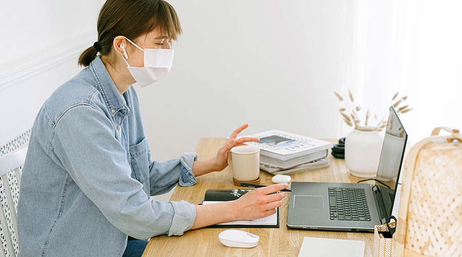 Woman in mask using laptop